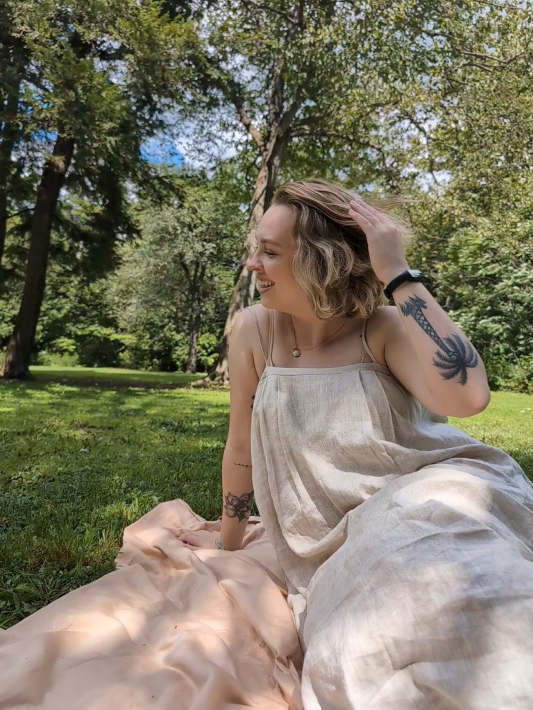 blonde woman sitting on a picnic blanket in a park